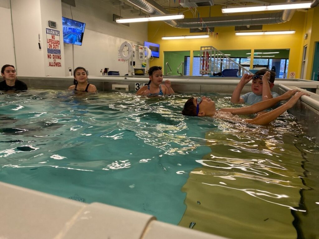 Children participating in SwimLabs Littleton kids swim lessons during the Gust Swim Camp water safety program